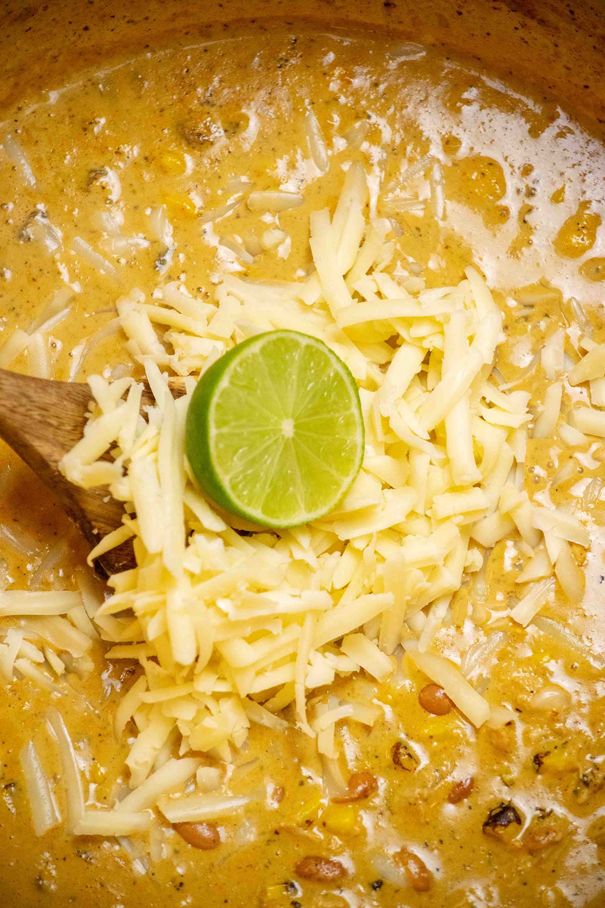 Add the chicken and veggies. Stir in the pinto beans, shredded chicken, and corn, then simmer for about 10 minutes until everything is heated through. Finish with the lime juice and cheddar cheese, stirring until the cheese is melted.