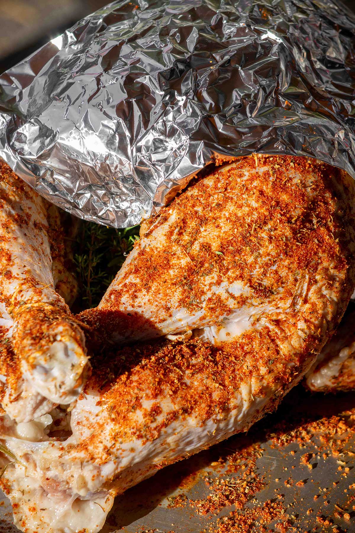 Add the aromatics. Stuff the cavity with the onion, lemon, rosemary, and thyme. Loosely cover the breast with a foil shield to keep it from cooking too quickly.