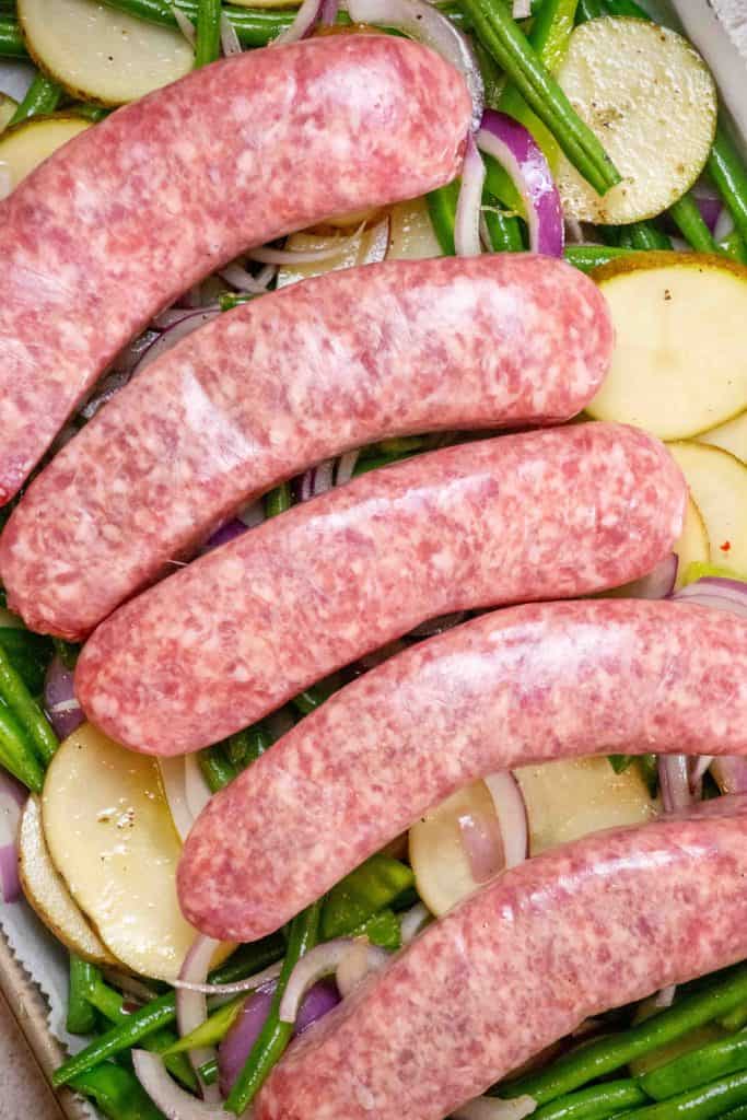 arrange tossed veggies on sheet pan, and top with brats