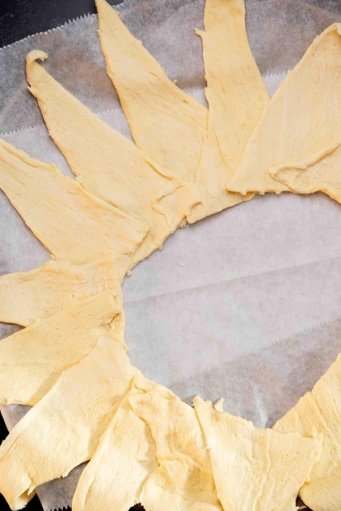 Line. a pizza pan with parchment, and arrange crescent triangles in a sunburst pattern