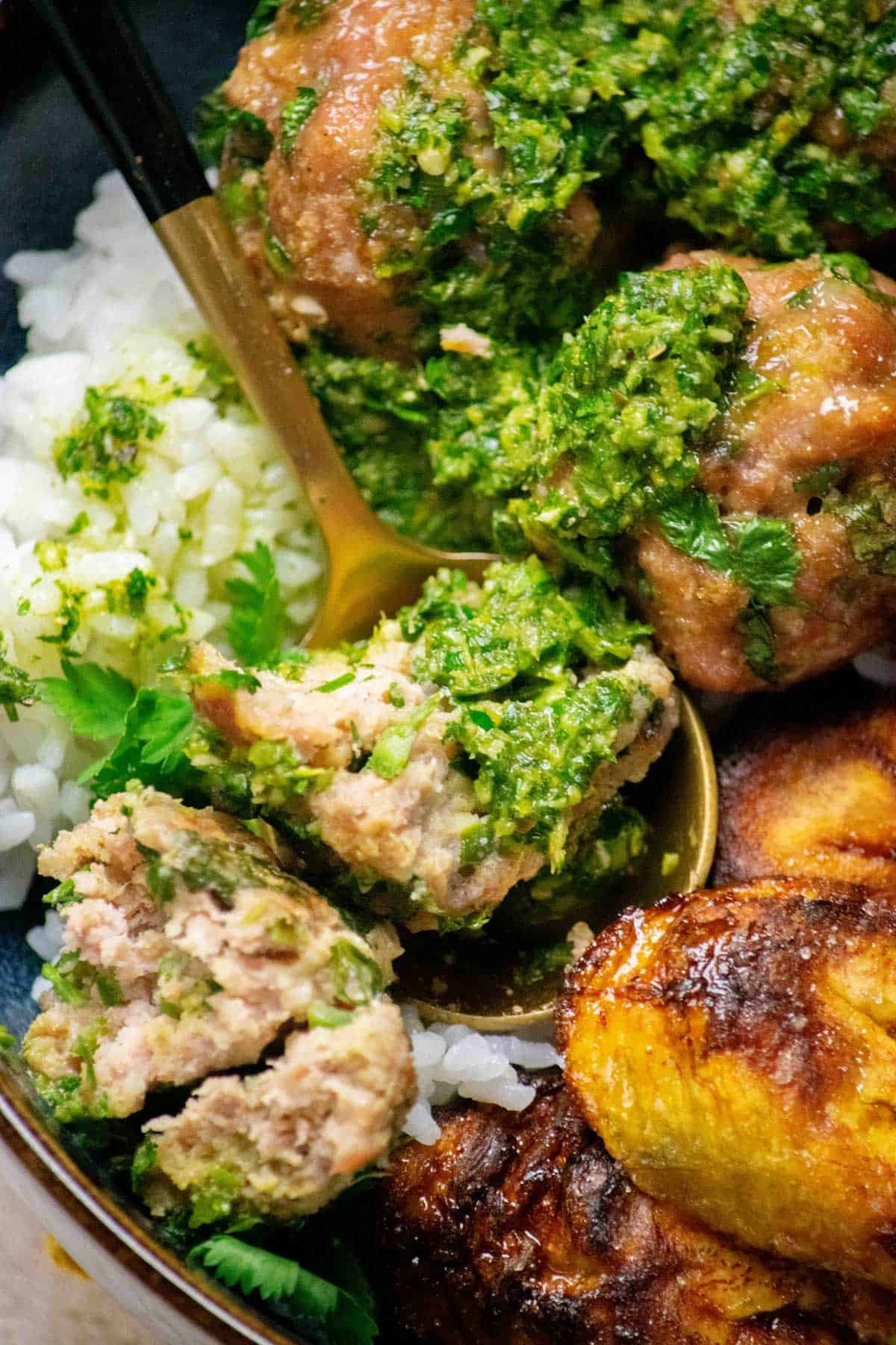 Cuban Mojo Meatballs cut in half, with Mojo sauce