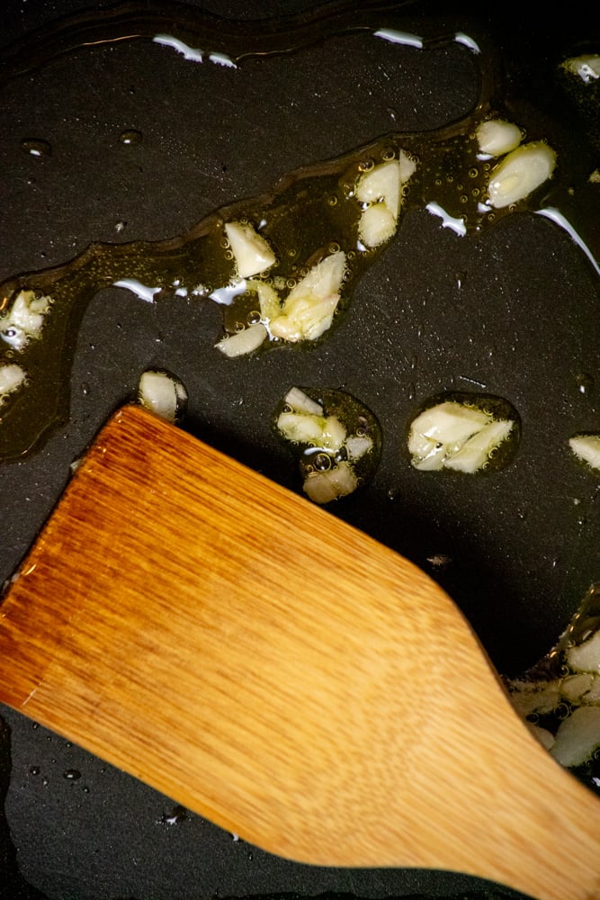 heat olive oil in a medium frying pan or skillet over medium heat, and add minced garlic. Cook, stirring occasionally for 1 minute, until fragrant, but not browned.
