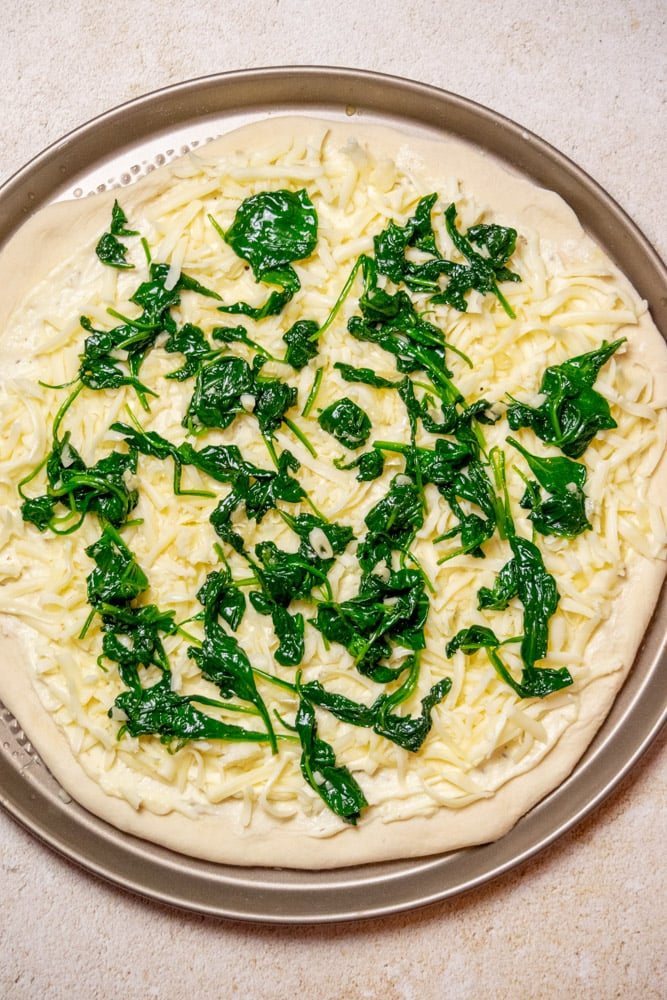 Add an evenly spaced layer of the garlic spinach.