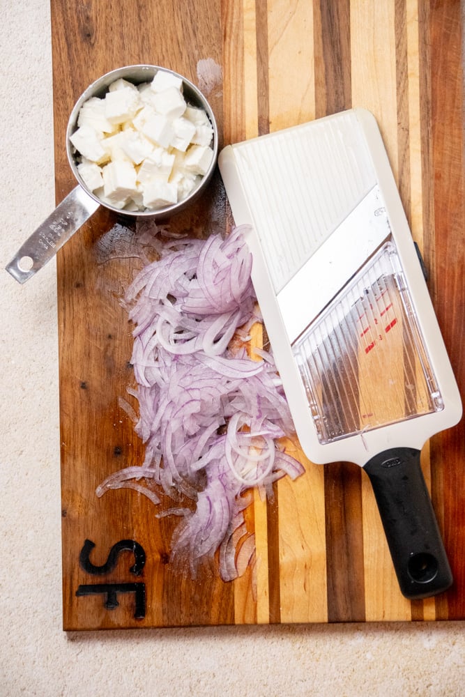 cut feta cheese into about 1" cubes. Using a mandoline slicer or sharp knife, slice your red onion into ultra thin slices.