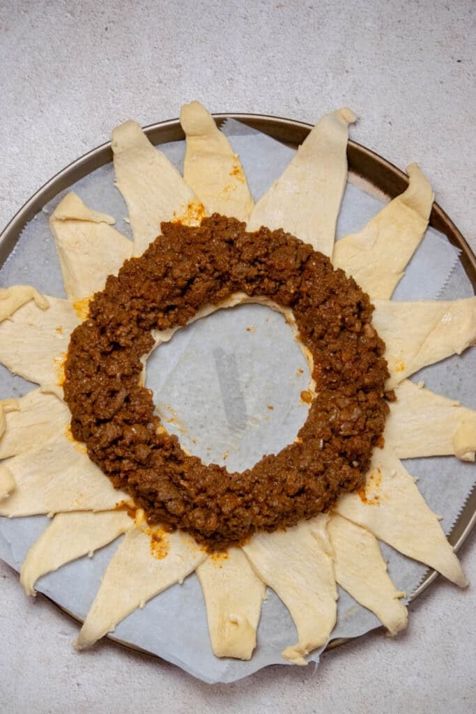arrange the ground beef in an even layer in the center, leaving a border at the inner edge. 