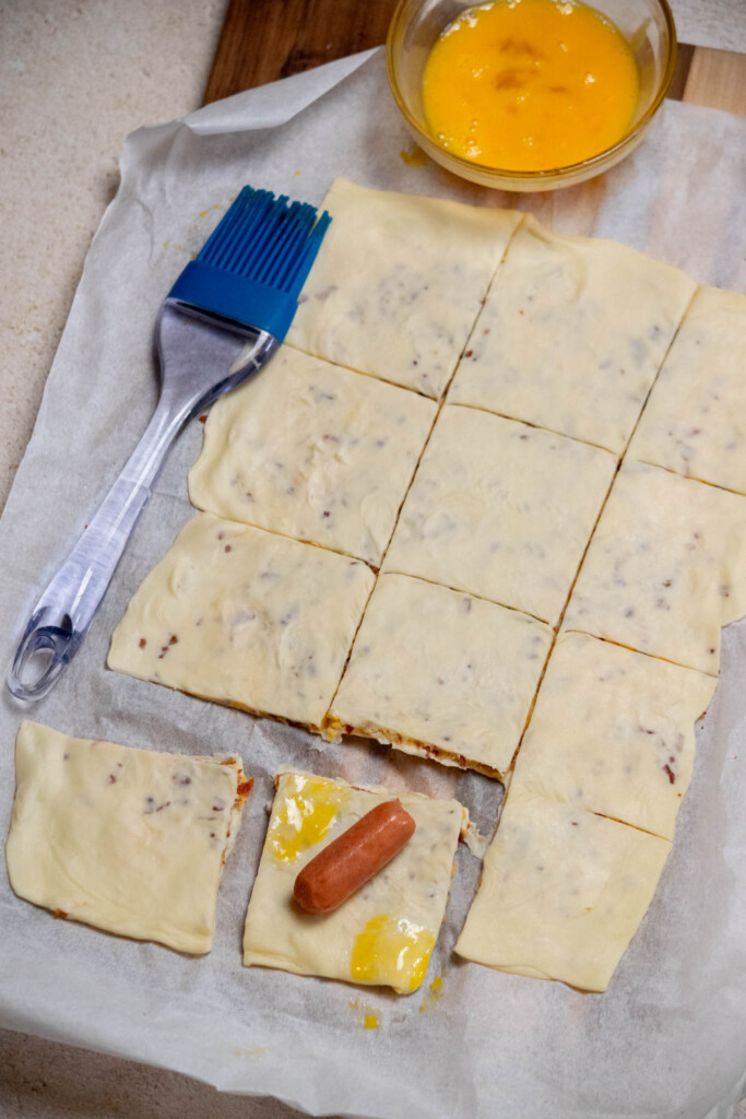 place the cocktail sausage diagonally in the center of each square, and moisten both outer corners with a light brush of beaten egg to help seal. 