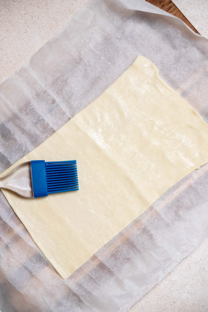 open up thawed puff pastry sheet, and cut in half, width wise. Brush lightly with water. 