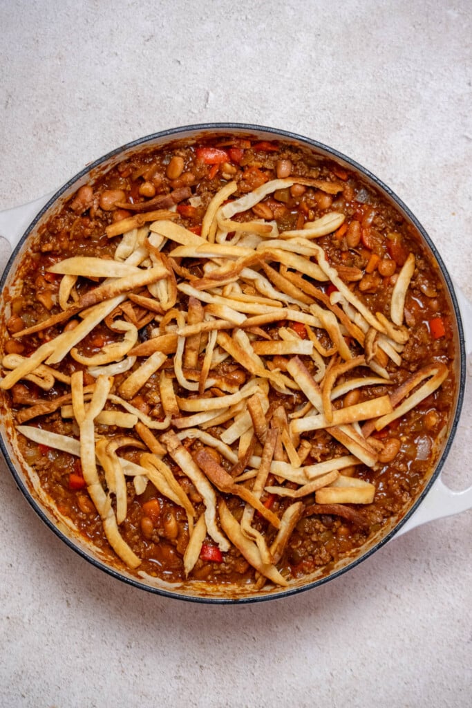 Turn off heat, and cover the meat mixture with an even layer of the reserved tortilla strips