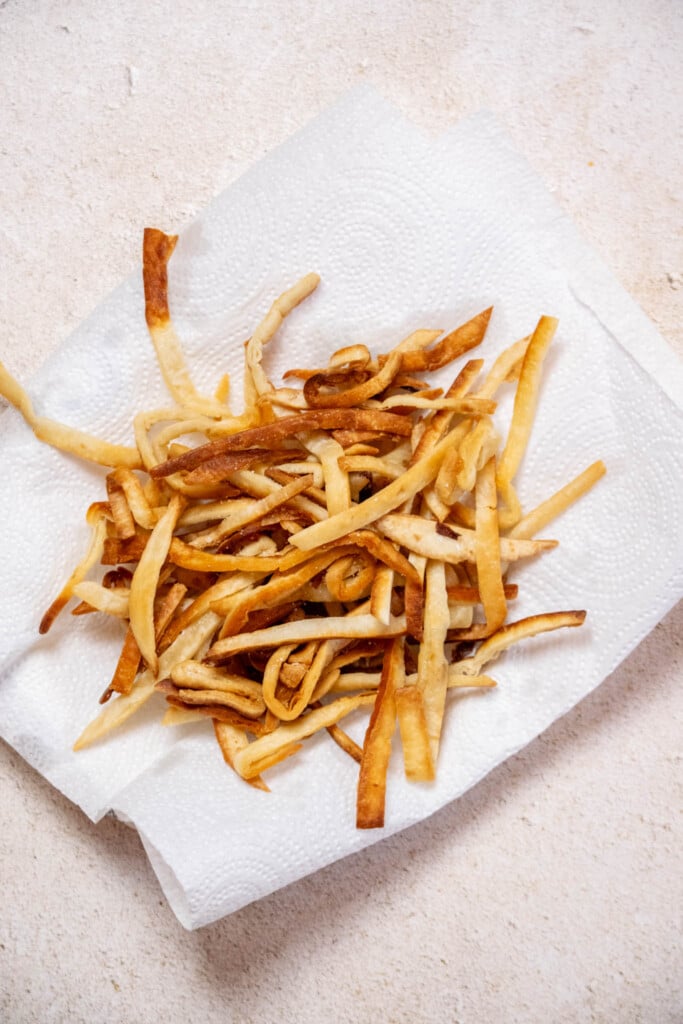 Transfer tortilla strips to a paper towel lined plate to drain, and season with a bit of salt. Set aside