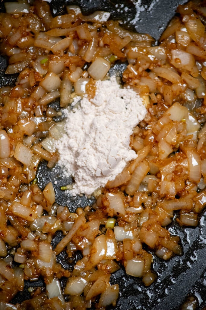 Add the flour to the pan, and stir well until completely incorporated with the butter, onions, and garlic. Cook one minute, stirring occasionally. 