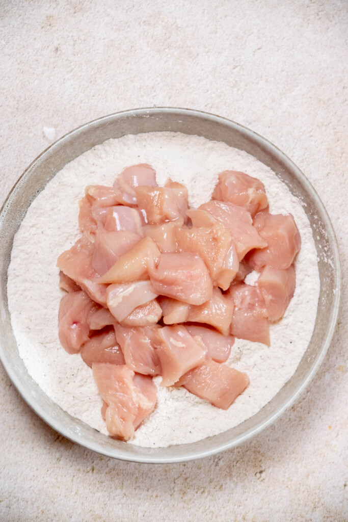 In a large bowl, whisk together flour, salt, and pepper. Cut chicken into bite sized pieces, and add to bowl with seasoned flour