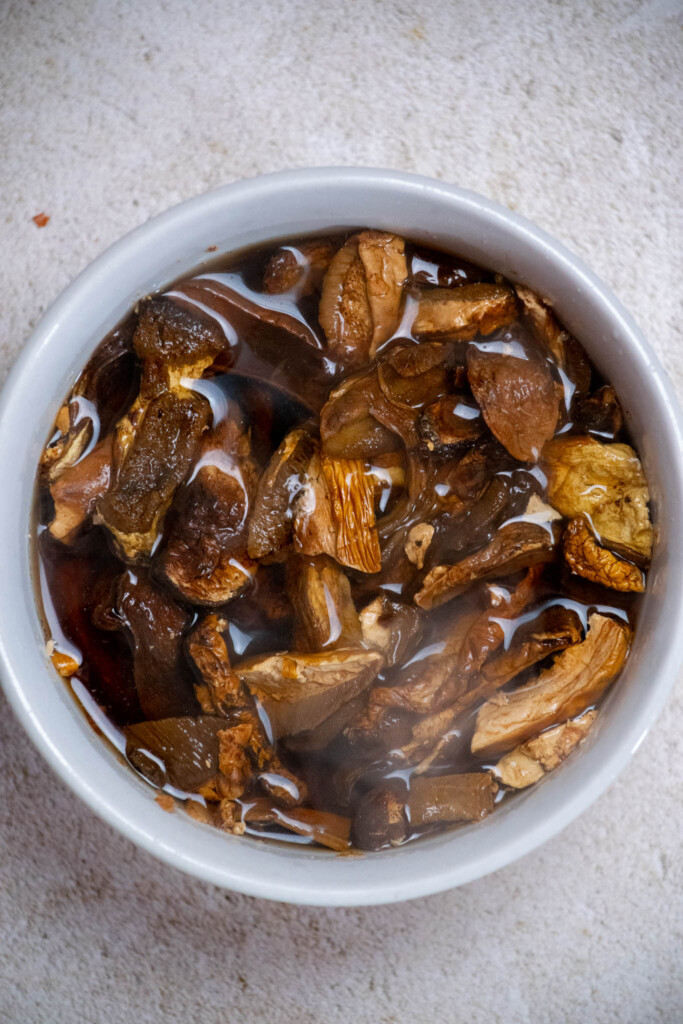 Soak the dried mushrooms in boiling water, adding a cover if needed to keep them fully submerged as they soak. 