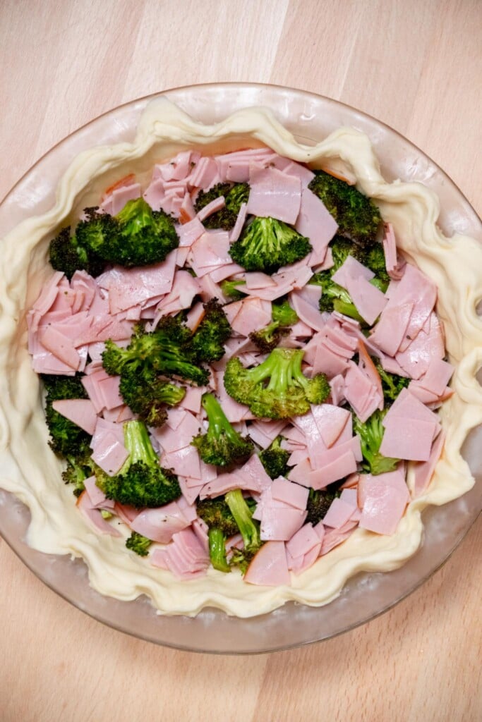 Once the dough is chilled and firm to the touch, layer in the chopped ham and roasted broccoli. 