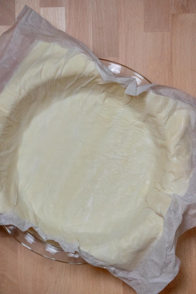Press the puff pastry sheet centered over the pie plate, then gently peel back the paper backing. 
