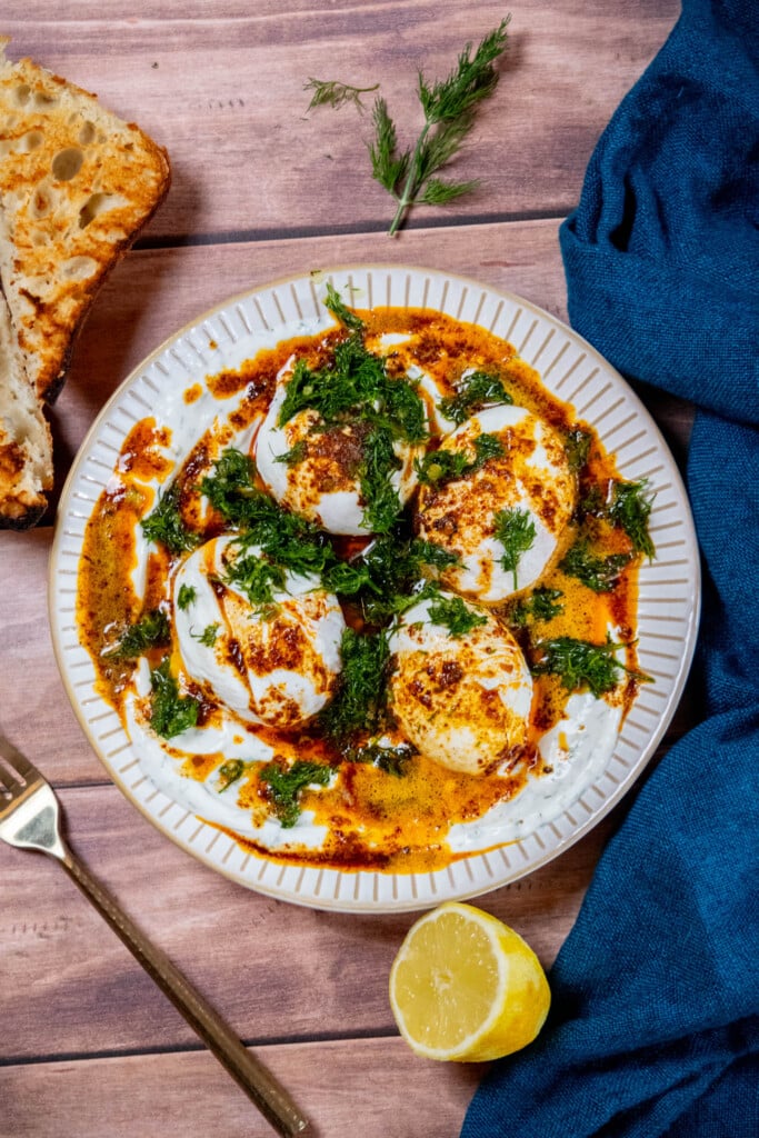  Plate up: smear the garlic yogurt on a plate, top with the poached eggs, drizzle with the butter, and top with dill mixture. 
