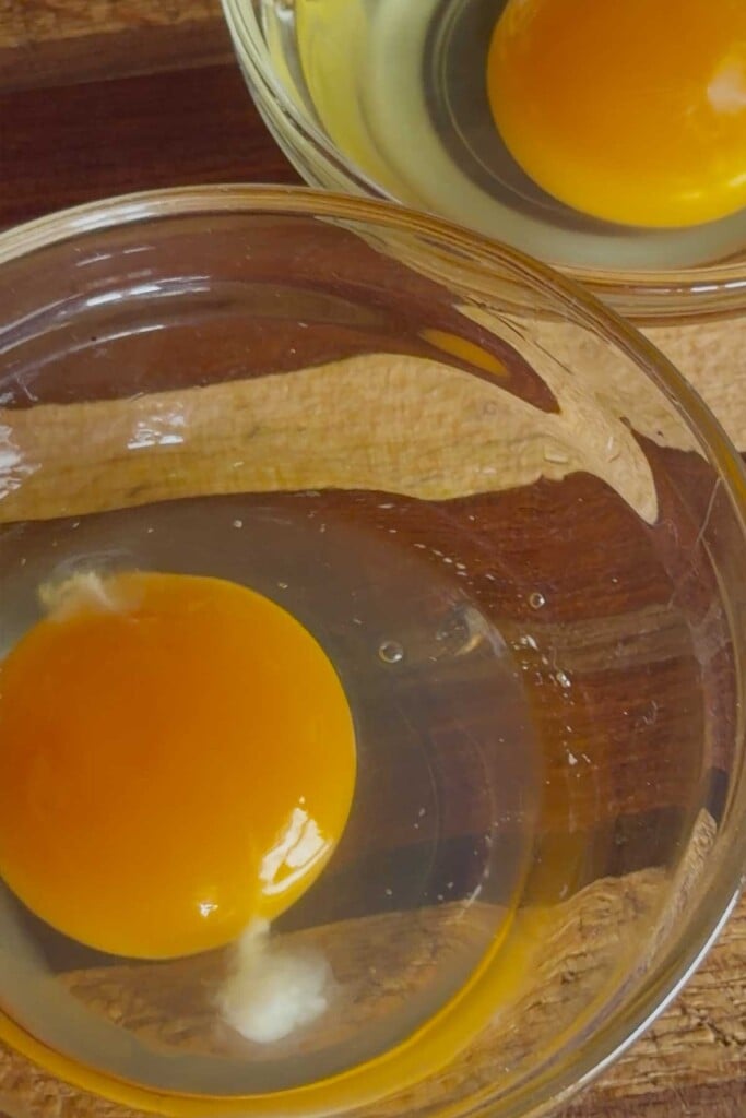 Once all eggs are separated, create a light vortex in the water by gently stirring with a spatula, and gently drop each egg one by one into the water. Poach for 3 minutes, then remove with a slotted spoon and blot with paper towels to remove excess water. 