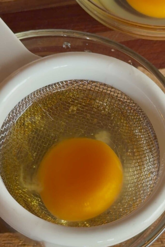 Heat a large saucepan of water with a pinch of salt and a tablespoon of white vinegar over medium heat to bring to a gentle simmer. Crack eggs over a fine mesh strainer and allow excess white to run off for 10-20 seconds, then transfer to small bowls or ramekins. 