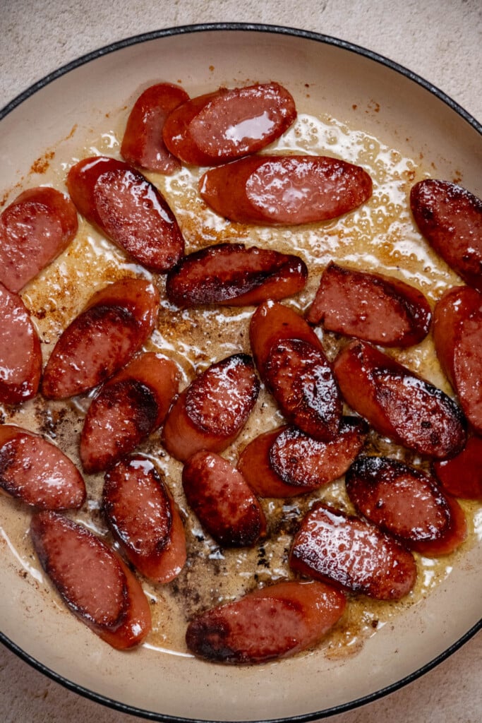 Heat olive oil in a large skillet, and arrange sausages in an even layer. Brown 3-4 minutes a side, and remove to a plate 