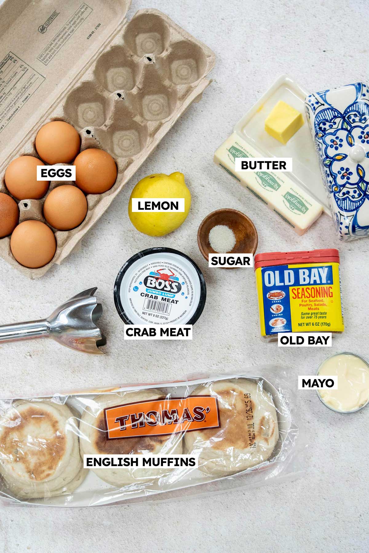 Ingredients to make crab benedict in bowls with labels on each one.