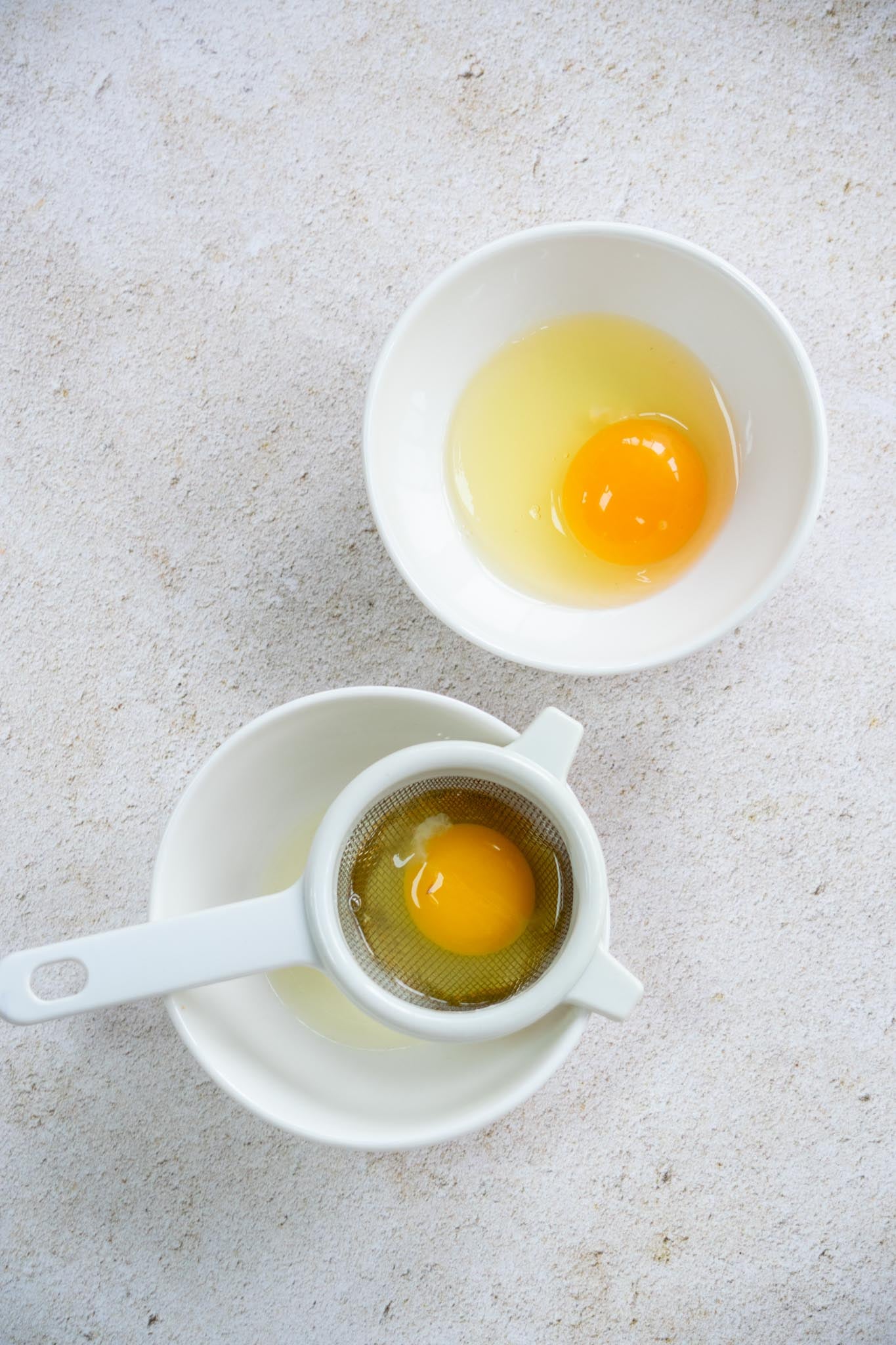 An egg draining in a small sieve.