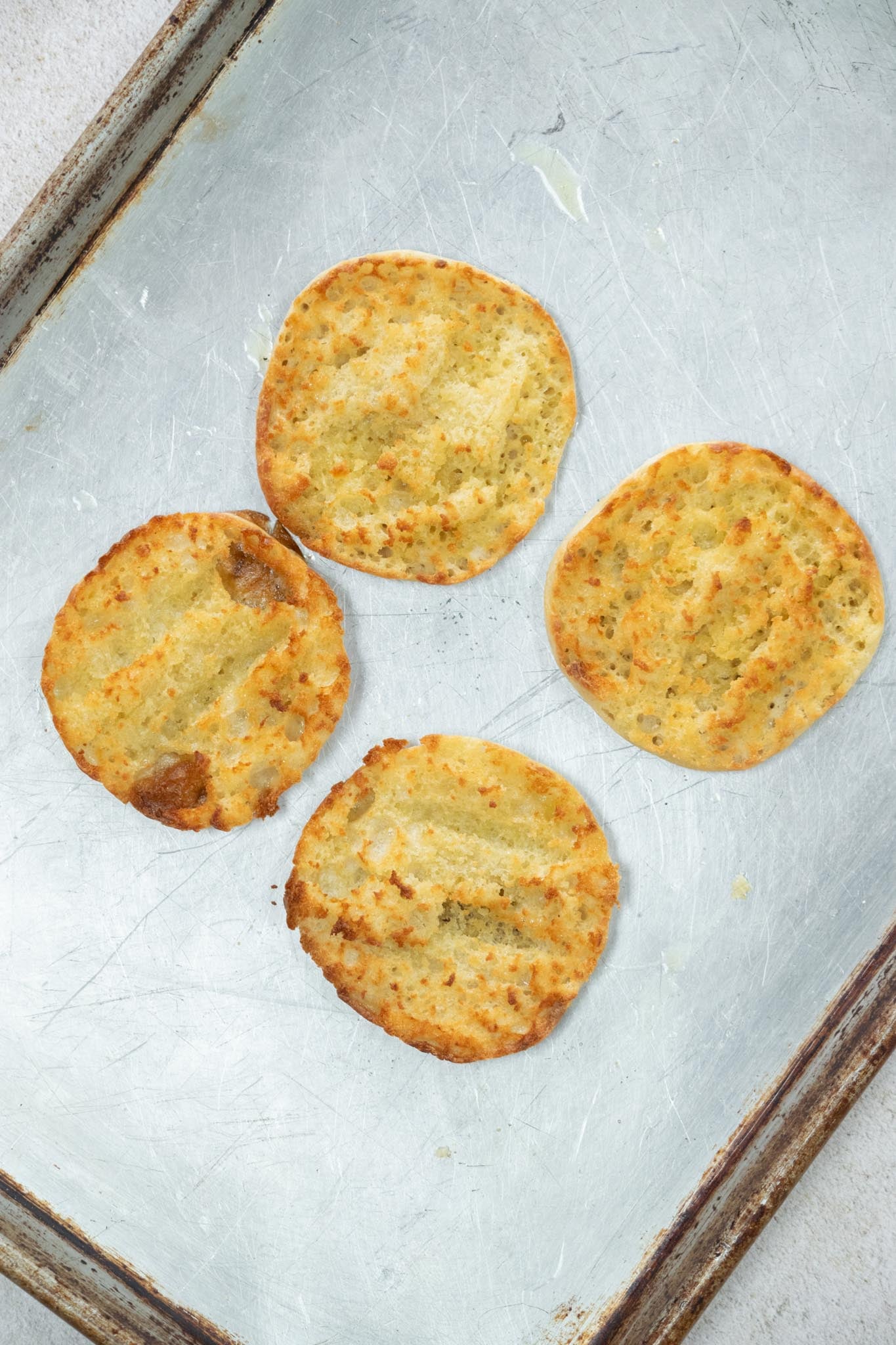 Toasted English muffins on a baking tray.