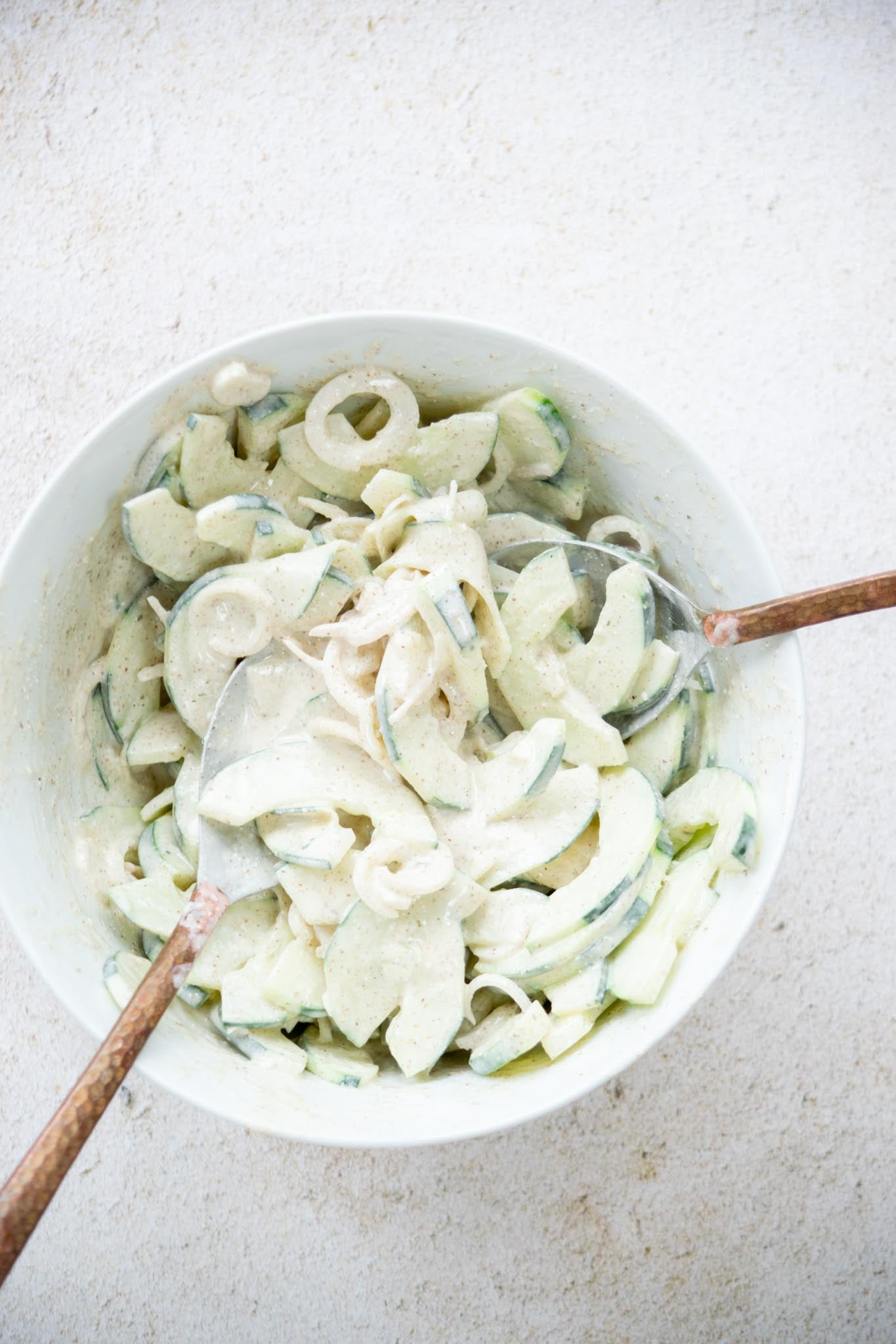 Dressing tossed with cucumbers and shallots.