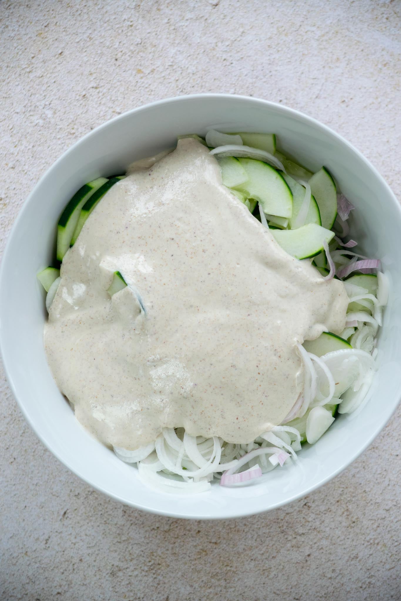 Dressing added to the bowl of cucumbers and shallots.