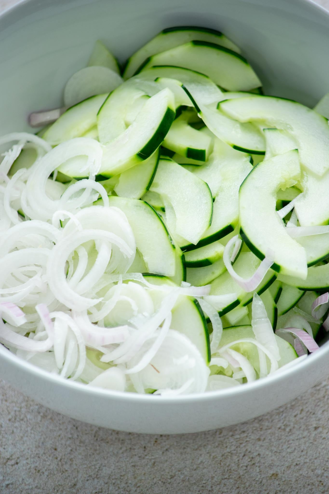 Sliced cucumbers and shallots in a bowl.