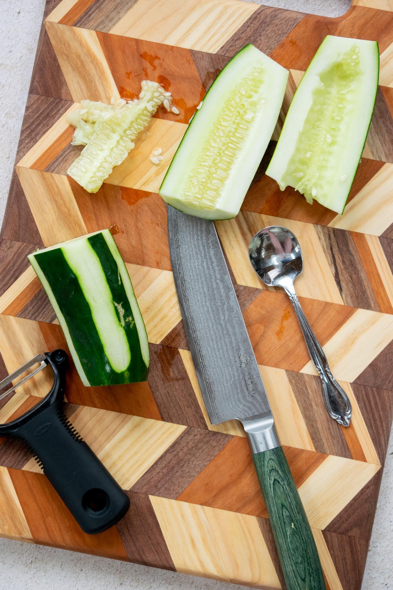 Cucumbers peeled, cut in half, and seeds scooped out on a cutting board.