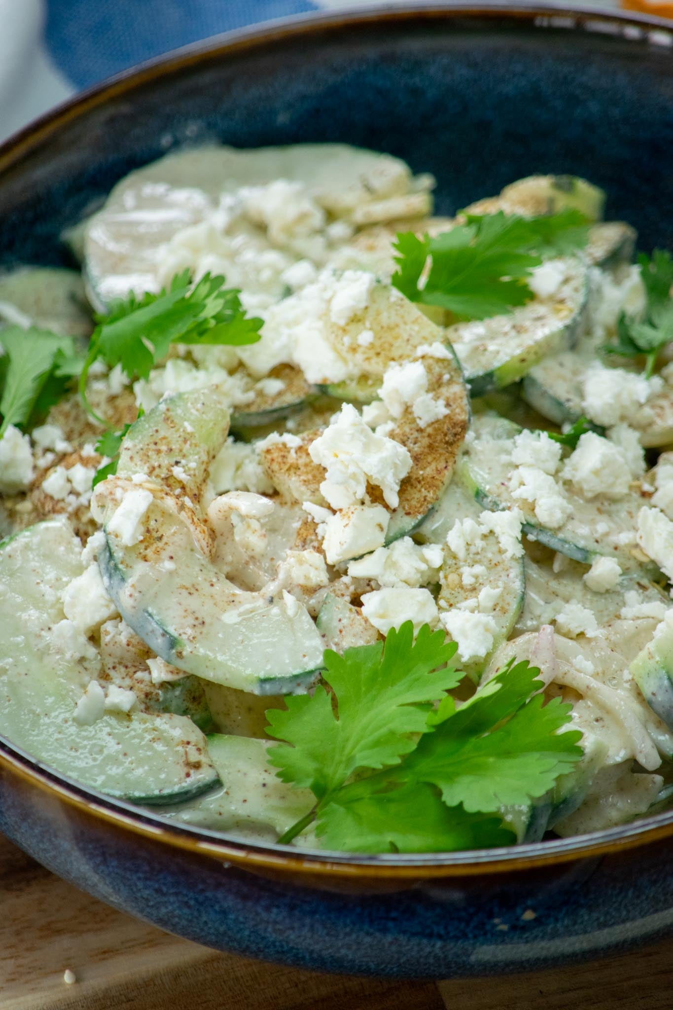A bowl of cucumber feta salad garnished with za'atar and cilantro leaves.