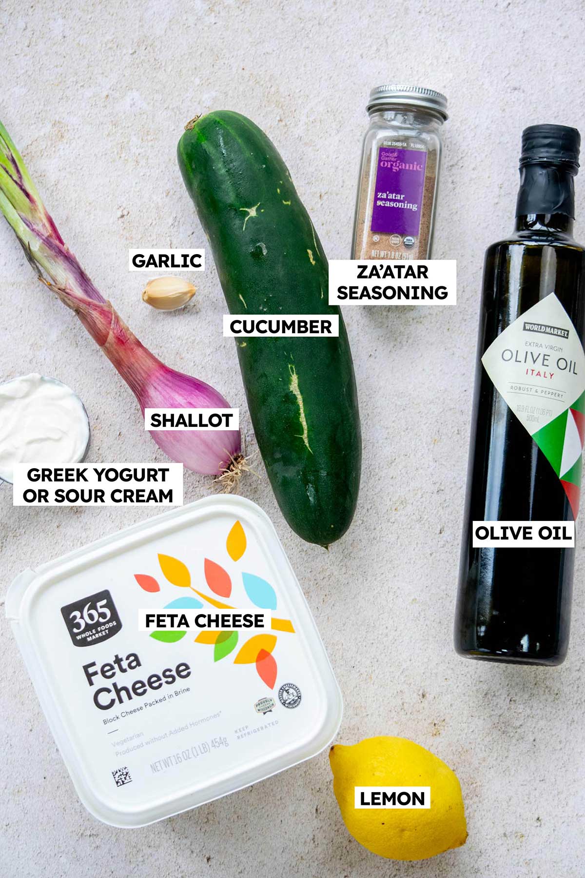 Ingredients to make a creamy cucumber feta salad on a countertop with text labels.