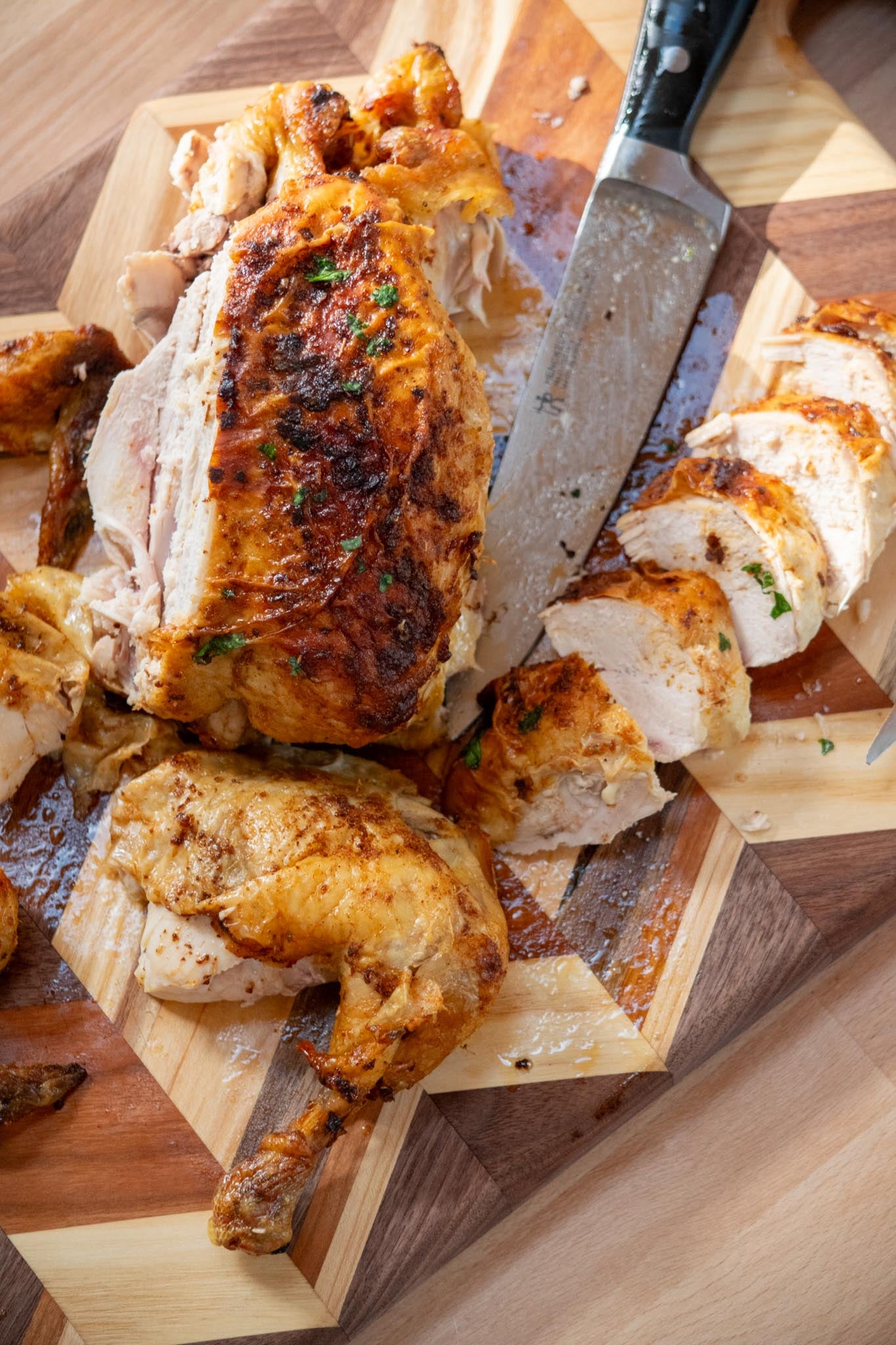 Air fryer roasted chicken on a cutting board with some slices cut and the knife resting to the side.