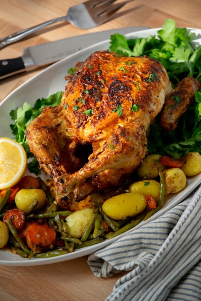 Air fryer roasted chicken on a platter with vegetables.